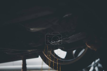 Téléchargez les photos : Car mechanic drain automatic transmission fluid - en image libre de droit