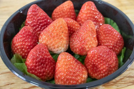 Photo for Strawberries in bowl on wooden table - Royalty Free Image