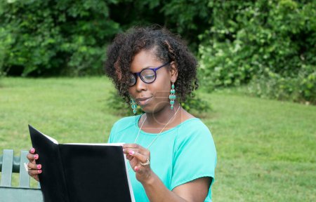 Foto de Joven mujer afroamericana leyendo al aire libre - Imagen libre de derechos
