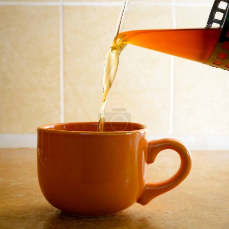 Téléchargez les photos : Verser le thé dans une tasse - en image libre de droit