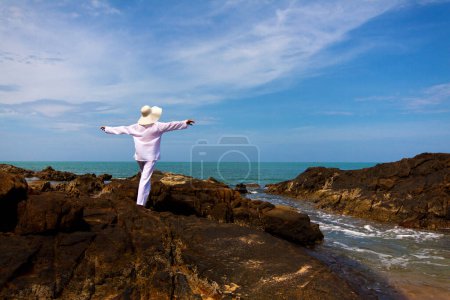 Téléchargez les photos : Plan panoramique de jeune femme avec des vêtements blancs et chapeau passer du temps à la plage pendant les vacances - en image libre de droit