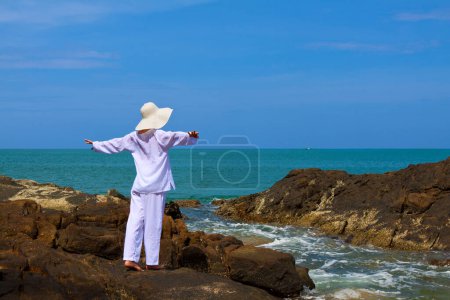Téléchargez les photos : Plan panoramique de jeune femme avec des vêtements blancs et chapeau passer du temps à la plage pendant les vacances - en image libre de droit