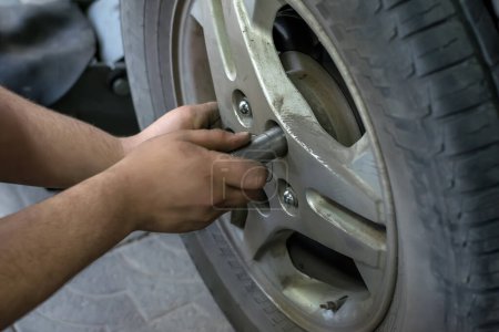 Photo for Human hands screw nuts in the wheel of the car - Royalty Free Image