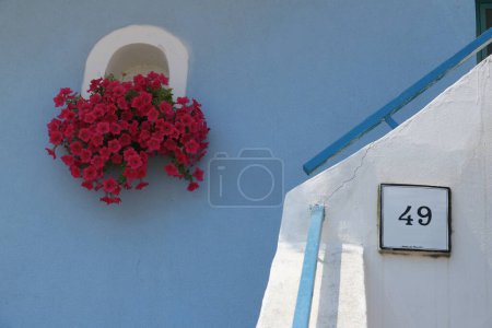 Foto de Florero de flores rojas en la fachada de la casa mediterránea. - Imagen libre de derechos