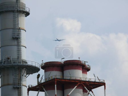 Photo for Turbigo, MIlan, 23/03/2009. Plane flies over the chimneys of a plant - Royalty Free Image