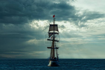 Photo for Antique tall ship, vessel leaving the harbor of The Hague, Scheveningen under a warm sunset and golden sky - Royalty Free Image