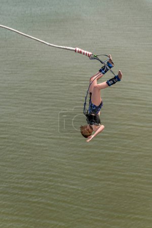 Téléchargez les photos : Bungee jumper jump from a platform hanging on the crane into the water against a pur blue spring sky of The Hague, Netherlands - en image libre de droit