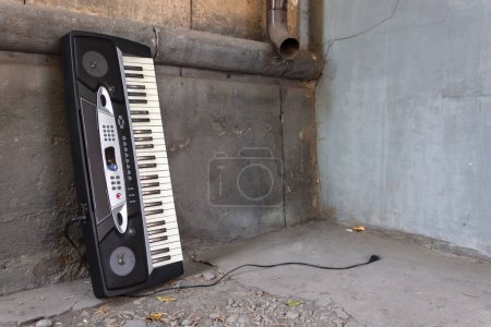 Téléchargez les photos : Un vieux synthétiseur musical abandonné se tient près du mur d'un bâtiment dans la rue - en image libre de droit