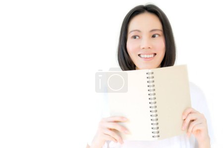 Photo for White girl smile and hides face behind a book - Royalty Free Image