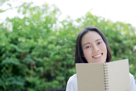 Photo for Serious young, beautiful girl holding an open book - Royalty Free Image