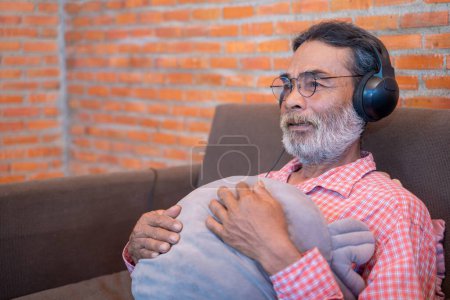 Photo for The old man listens to the music from the headphones - Royalty Free Image