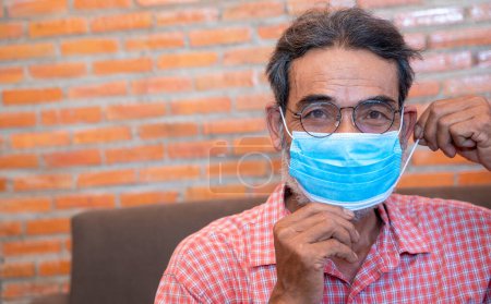 Téléchargez les photos : Portrait d'un homme âgé souriant prêt à porter un masque de protection - en image libre de droit