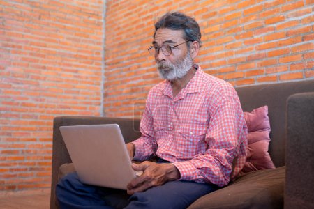 Téléchargez les photos : Vieil homme apprenant à utiliser un ordinateur portable à la maison. - en image libre de droit