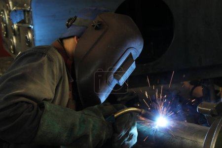 Welder working with steel at industrial factory