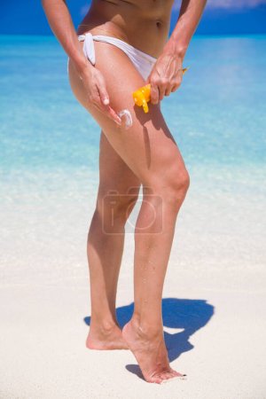 Foto de Mujer Aplicando protector solar en la playa sobre fondo - Imagen libre de derechos