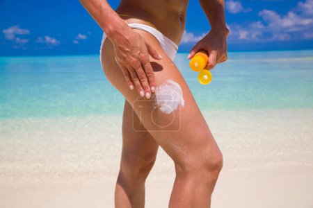 Photo for Woman Applying Sunscreen on the beach - Royalty Free Image