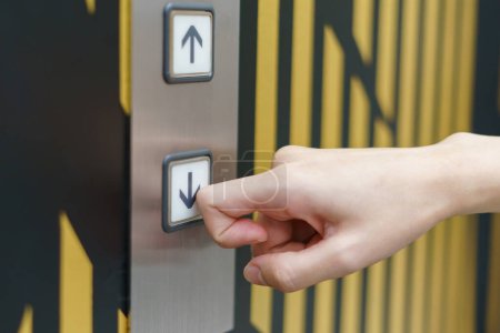Photo for "Woman finger pressing a down button of elevator button inside th" - Royalty Free Image
