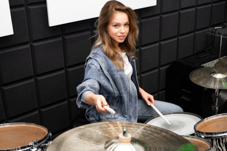 Photo for Creativity and music. Young beautiful girl plays the drums. Recording Studio. Musical equipment. - Royalty Free Image