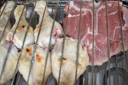 Téléchargez les photos : Poulet grillé et steaks sur un gril dans la cuisine - en image libre de droit