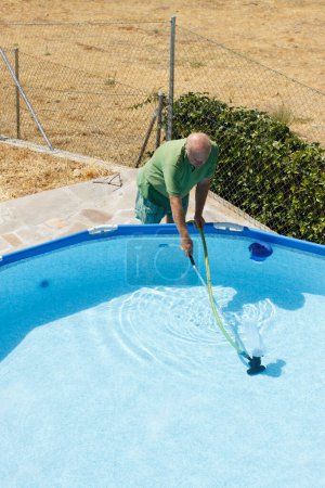 Téléchargez les photos : Homme nettoyage piscine extérieure - en image libre de droit