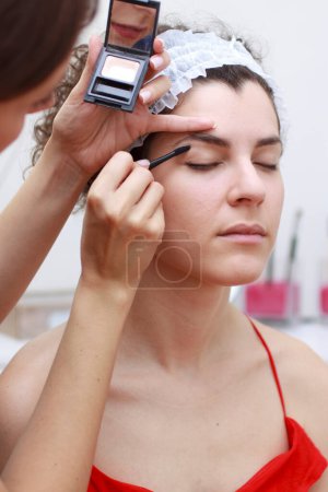 Foto de Mujer joven aplicando maquillaje a cliente femenino en spa - Imagen libre de derechos