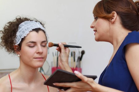 Téléchargez les photos : Jeune femme appliquant le maquillage à la cliente dans le spa - en image libre de droit