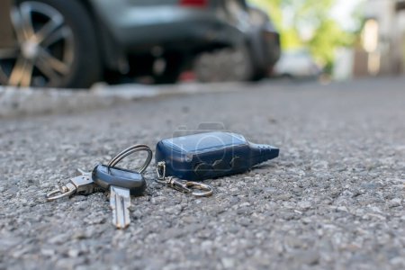 Téléchargez les photos : Le porte-clés perdu, télécommande d'alarme de voiture, se trouve sur le trottoir asphalté de la route - en image libre de droit
