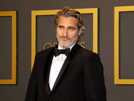 Foto de Joaquín Phoenix en pajarita y traje negro posando en cámara, ceremonia Oscar - Imagen libre de derechos