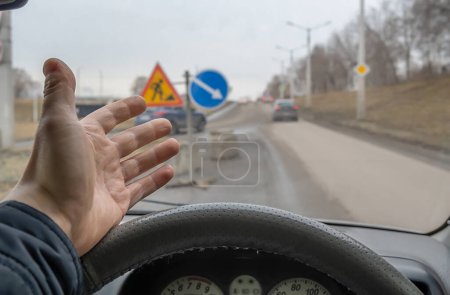 Téléchargez les photos : La paume d'un conducteur au volant d'une voiture indignée par les réparations routières et les panneaux routiers installés - en image libre de droit