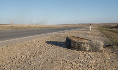 Photo for Torn car tire is lying on the side of the road - Royalty Free Image