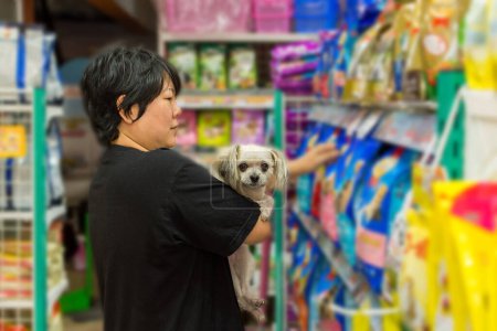 Foto de Las mujeres y su perro de compras en tienda de mascotas - Imagen libre de derechos