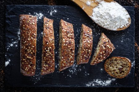 Téléchargez les photos : Gros plan de pain avec farine sur fond d'ardoise - en image libre de droit