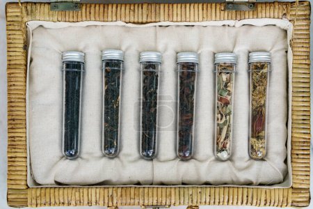 Téléchargez les photos : Six tubes de différentes feuilles collection de thés dans le panier en osier - en image libre de droit