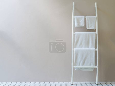 Foto de Toallas blancas colgadas en el soporte de escaleras de madera blanca. - Imagen libre de derechos