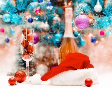Foto de Bolas de purpurina roja en una copa de vino grande sobre el fondo de un árbol de Navidad decorado - Imagen libre de derechos