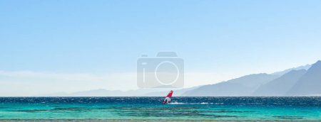 Téléchargez les photos : Balades en surf dans la mer Rouge sur fond de hautes montagnes rocheuses - en image libre de droit
