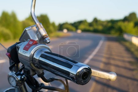 Foto de View of handlebar grips of the motorcycle on the country road background closeup - Imagen libre de derechos