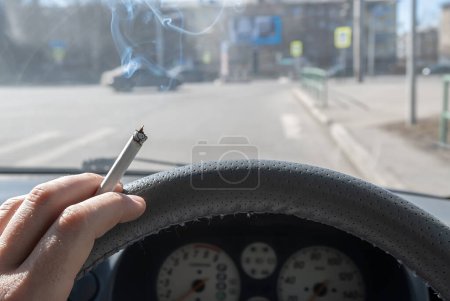 Téléchargez les photos : Une cigarette dans la main d'un conducteur de voiture fumeur - en image libre de droit