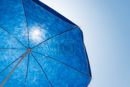 Foto de Sombrilla azul de la playa contra el cielo azul soleado - Imagen libre de derechos