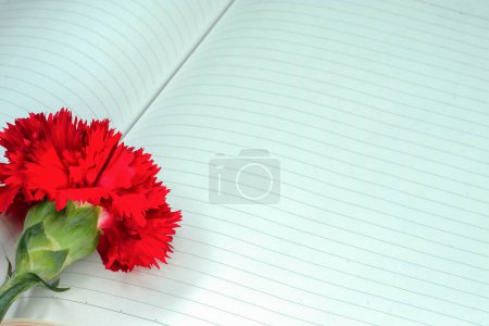 Photo for A red carnation on a notebook - Royalty Free Image