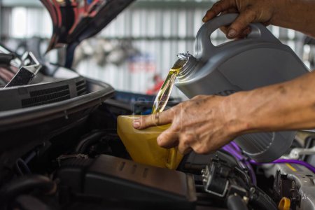 Téléchargez les photos : Mécanicien de voiture remplit une huile moteur lubrifiant frais - en image libre de droit