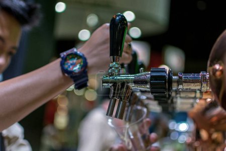 Téléchargez les photos : Barman ou barman versant une bière de bière à bière tirée du robinet de bière - en image libre de droit