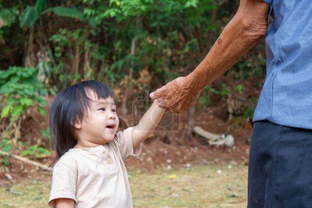 Téléchargez les photos : Asiatique petite fille enfant jouer dans le jardin heureux avec sa famille. - en image libre de droit