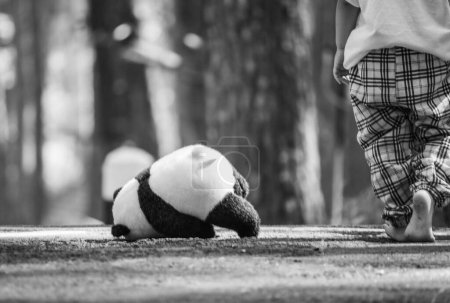 Photo for Rear of Asian little child girl walking barefoot and abandoned the teddy bear in solitude on the road. - Royalty Free Image