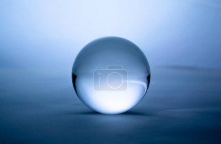 Téléchargez les photos : "Boule de cristal en verre transparent sur fond dégradé bleu." - en image libre de droit