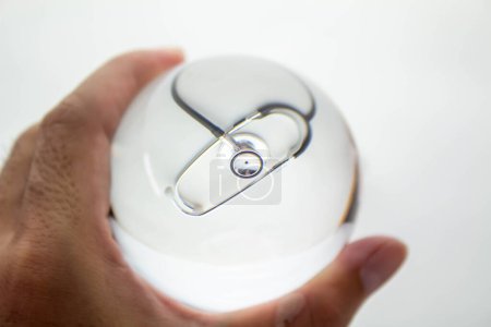 Téléchargez les photos : "Gros plan de la sphère de boule de verre cristal tenant la main révélant le stéthoscope médical interne et la seringue sur fond de dégradé gris." - en image libre de droit