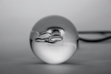 Téléchargez les photos : "sphère de boule de cristal en verre révélant le stéthoscope médical interne sur fond gradient gris." - en image libre de droit