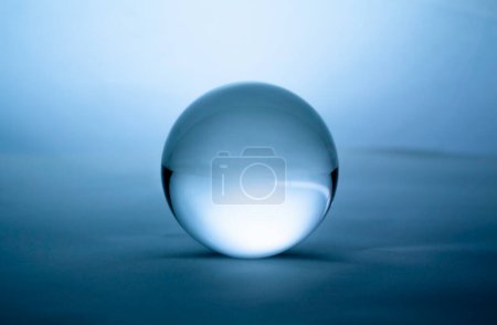 Téléchargez les photos : "Boule de cristal en verre transparent sur fond dégradé bleu." - en image libre de droit