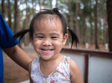 Foto de Lindo asiático pequeño niño chica sentado en el jardín con smiley cara - Imagen libre de derechos