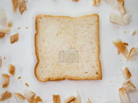 Téléchargez les photos : "Miettes de pain éparpillées et pain tranché sur fond de table blanche." - en image libre de droit